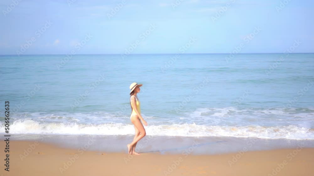 Sexy slender female model in swimsuit walking on sandy beach by sea waves, slow motion Sexy slender female model in swimsuit walking on sandy beach by sea waves, slow motion
