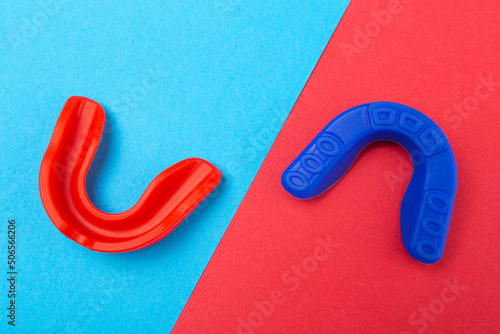 two mouthguards for boxing, blue and red, lie on a red-blue background, concept