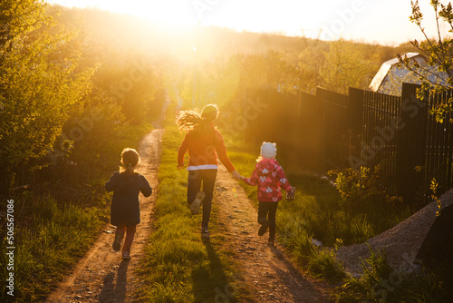 a group of kids play and spend time together in nature. three children of friends run through a dear summer evening