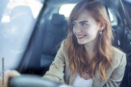Beautiful smiling young redhead woman behind steering wheel driving car. © Graphicroyalty