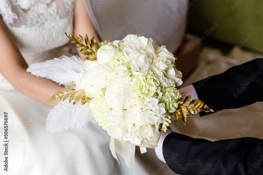 Groom and bride holding white bouquet together Groom and bride holding white bouquet together