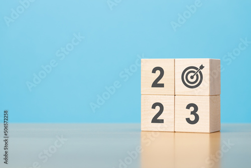 New year 2023 goal. Wooden blocks with 2023 and target icon on wooden table blue background copy space.
