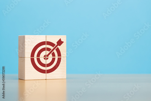 Wooden blocks with red target icon on wooden table blue background copy space. The concept of strategy, goals.