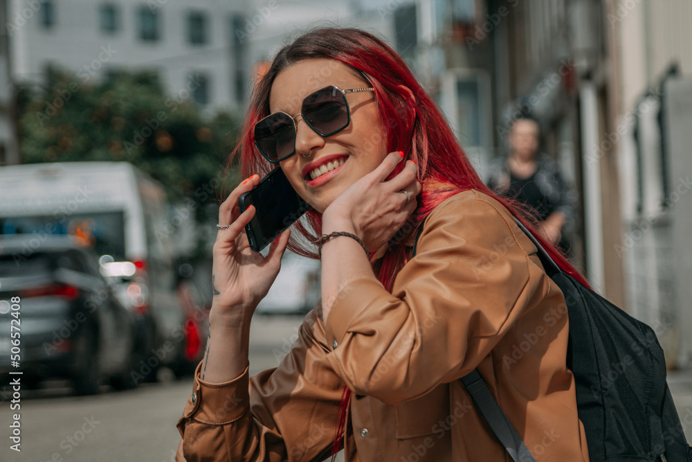 Fototapeta premium relaxed red-haired tourist woman with phone and backpack on the street