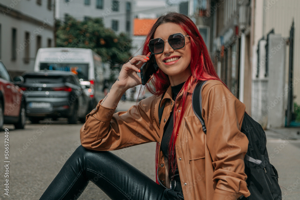 Obraz premium relaxed red-haired tourist woman with phone and backpack on the street