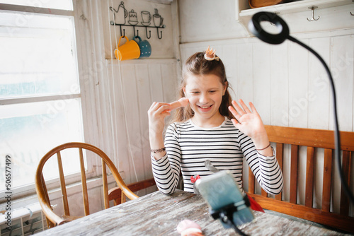 Preteen girl in kitchen shoots video with cosmetics, video blogger and streamer
