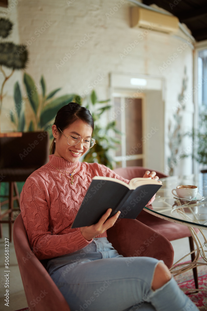 A multicultural girl is reading a book in a coffee shop and having fun. A multicultural girl is reading a book in a coffee shop and having fun.