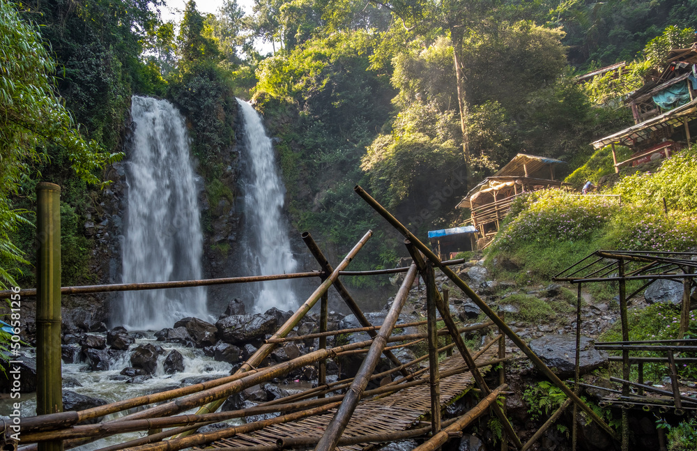 The view of twin falls with traditional bamboo bridge surround by cliff at Cinulang Falls, Bandung, West Java