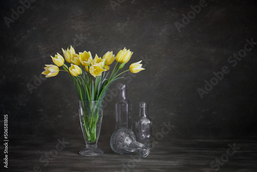 Still life. Tulips Bouquet in a glass on a wooden table. Rustic style.