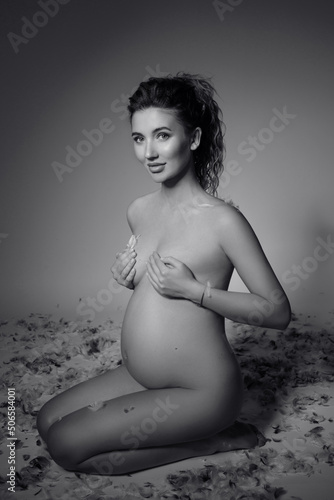 A young white pregnant woman is nine months pregnant on a bright background