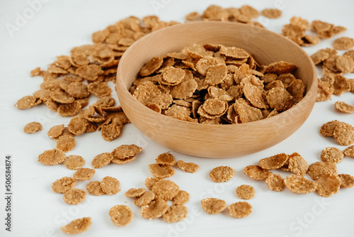 Quadro su tela Crispy healthy dry cereal flakes in a wooden bowl on white background