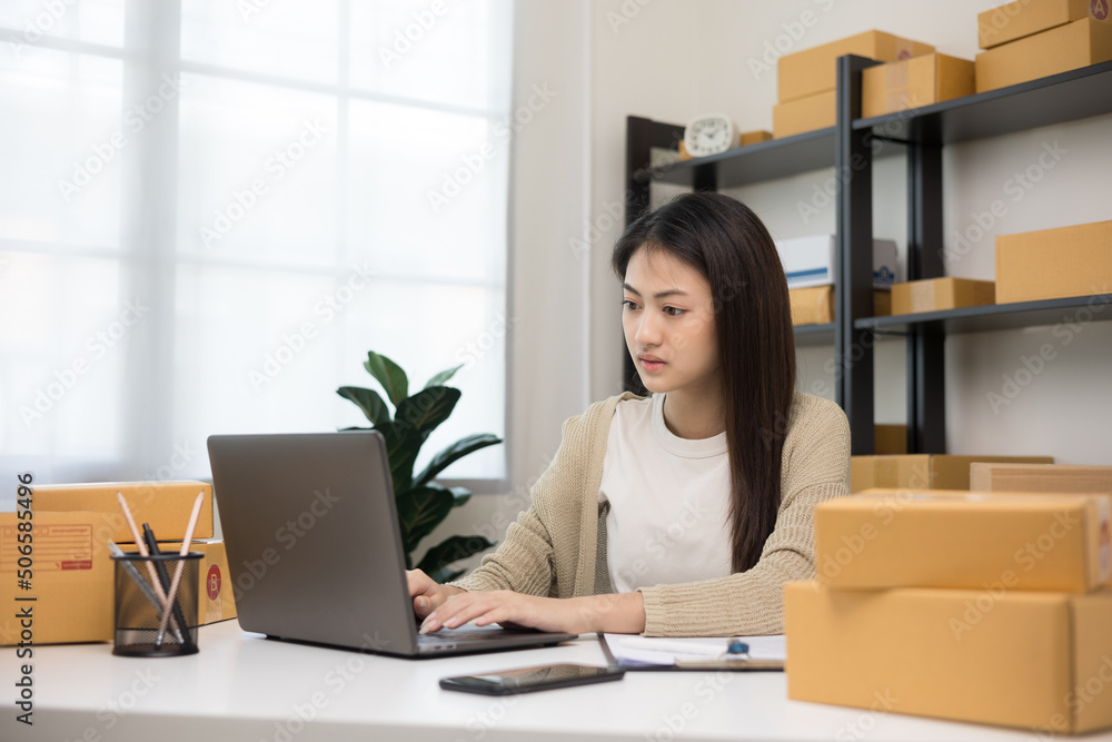 Young asian entrepreneur woman checking product on stock take note with laptop. Business woman working SME online at home. Check address on parcel. Small business owner start up freelance concept. Young asian entrepreneur woman checking product on stock take note with laptop. Business woman working SME online at home. Check address on parcel. Small business owner start up freelance concept.