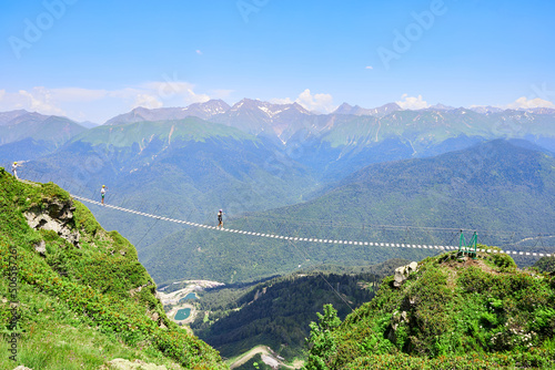 People walk on a suspension bridge in the mountains