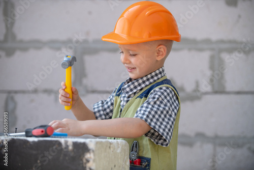 Little boy in orange protective helmet with instruments for renovation. Repair home.