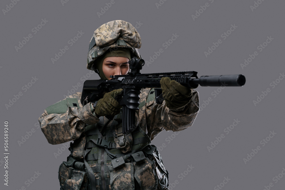 Portrait of militant woman dressed in camouflage clothes aiming rifle against gray background. Portrait of militant woman dressed in camouflage clothes aiming rifle against gray background.