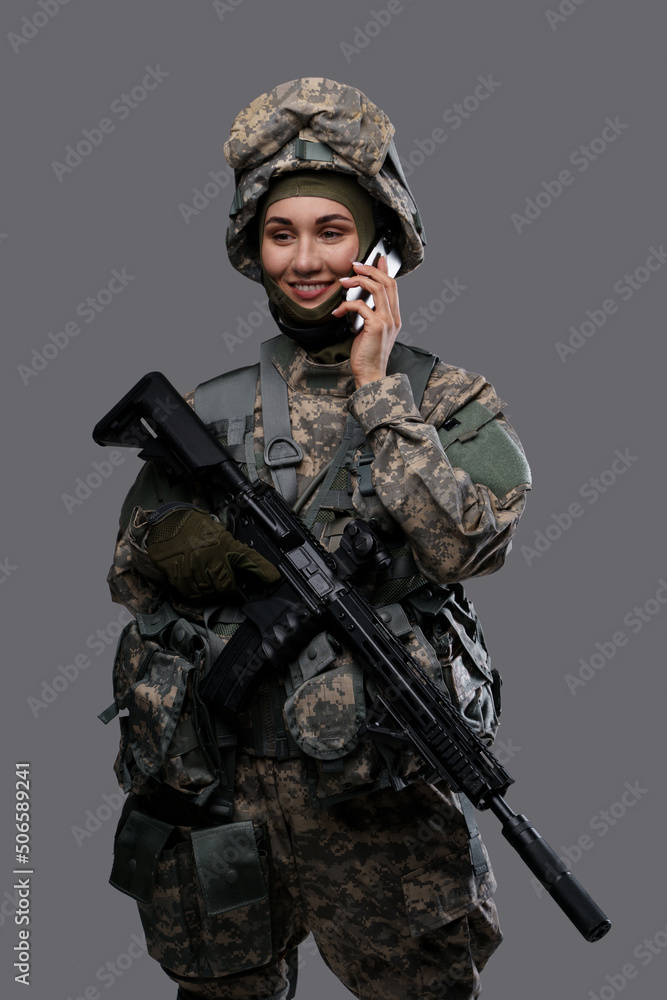 Portrait of joyful woman soldier dressed in camouflage clothes talking on phone. Portrait of joyful woman soldier dressed in camouflage clothes talking on phone.