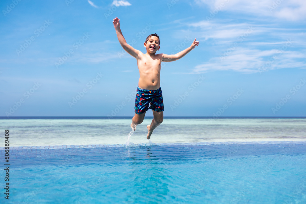 Funny kid jumping into a infinity swimming pool Funny kid jumping into a infinity swimming pool
