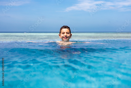 Little kid in a infinity pool near the ocean © Victor