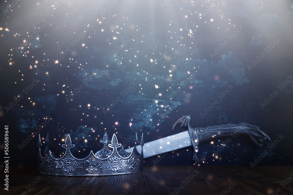 low key image of beautiful queen or king crown next to sword. fantasy ...