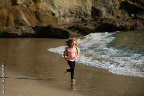 Child running through water close to shore along the sea beach. A boy runs along the sea coast. Rest of children on summer vacation. Run and healthy sport for children.