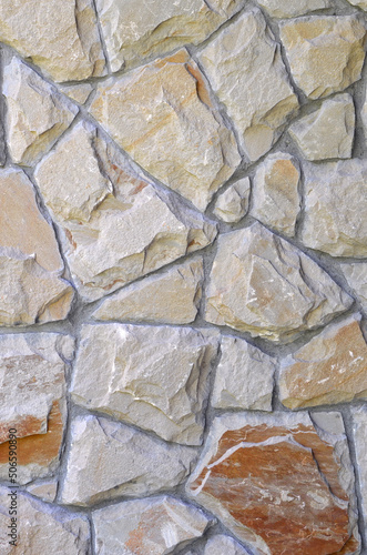 Exterior wall of broken granite stone in gray-brown tones. Wall pattern. Wall natural stone cladding background.