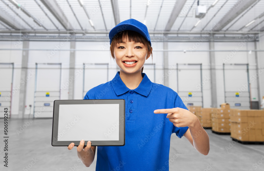 logistics, shipping and job concept - happy smiling delivery woman in blue uniform with tablet pc computer over warehouse background logistics, shipping and job concept - happy smiling delivery woman in blue uniform with tablet pc computer over warehouse background