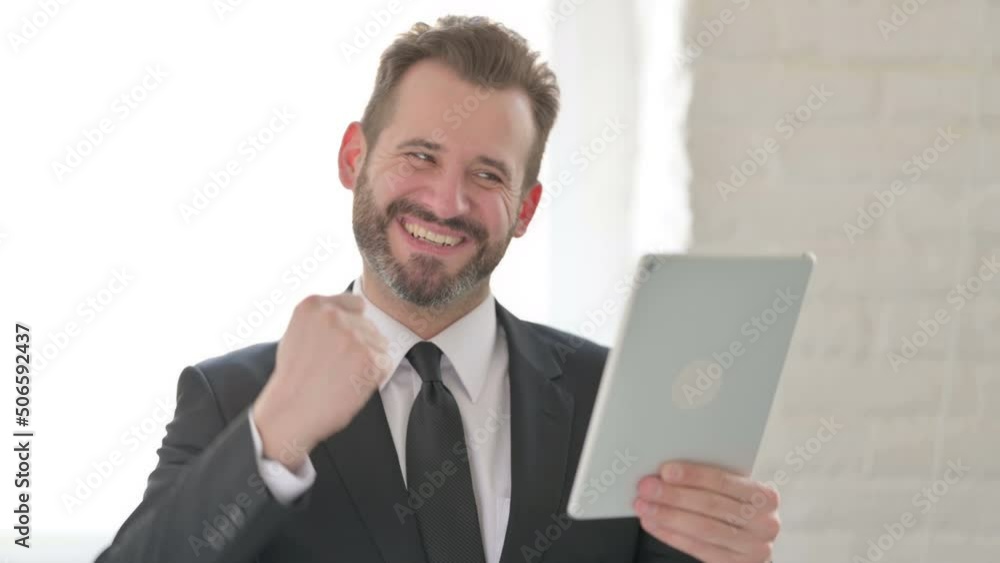 Young Businessman Celebrating on Tablet in Office Young Businessman Celebrating on Tablet in Office
