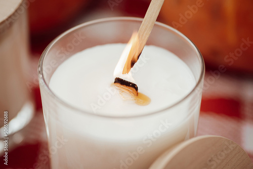 Igniting white aromatic candle with wooden wick. Aromatherapy concept