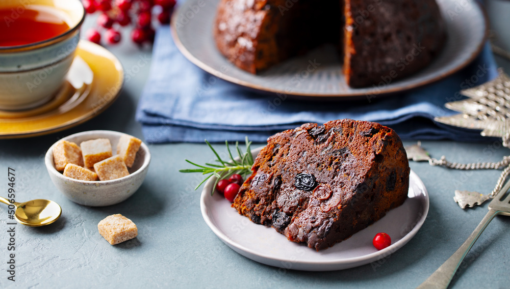 Christmas pudding, fruit cake with cup of tea. Traditional festive dessert. Grey background. Close up.
