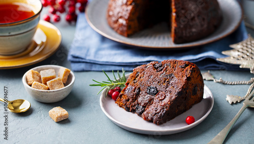 Christmas pudding  fruit cake with cup of tea. Traditional festive dessert. Grey background. Close up.