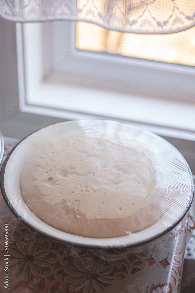 Yeast dough in a bowl on the table, sourdough baking. Yeast dough in a bowl on the table, sourdough baking.