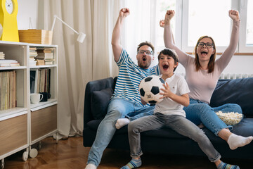 family cheering and watching soccer game at home