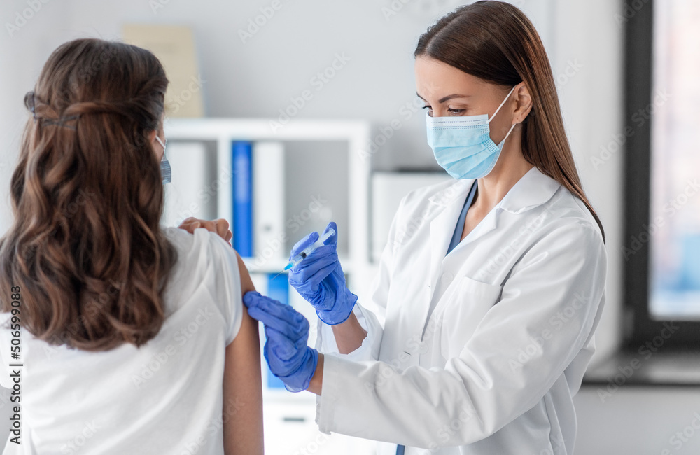 health, medicine and pandemic concept - female doctor or nurse wearing protective medical mask and gloves with syringe vaccinating patient at hospital health, medicine and pandemic concept - female doctor or nurse wearing protective medical mask and gloves with syringe vaccinating patient at hospital