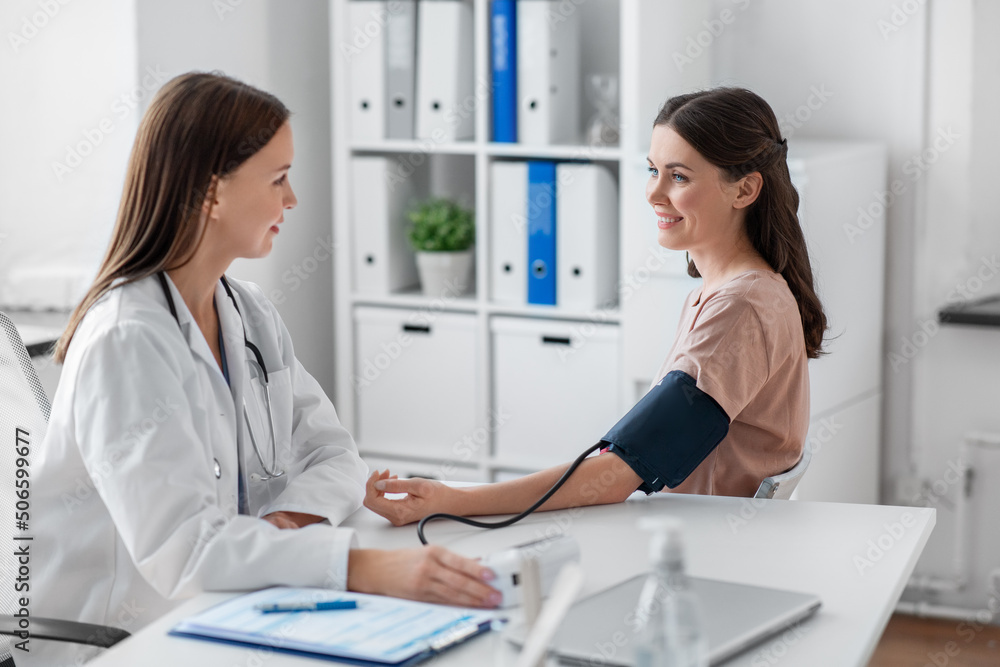 medicine, healthcare and people concept - smiling female doctor with tonometer measuring woman patient's blood pressure at hospital medicine, healthcare and people concept - smiling female doctor with tonometer measuring woman patient's blood pressure at hospital