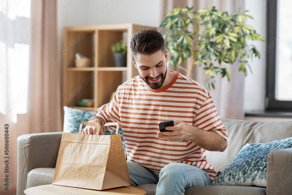 communication, leisure and people concept - happy smiling man using smartphone for takeaway food order check up at home communication, leisure and people concept - happy smiling man using smartphone for takeaway food order check up at home