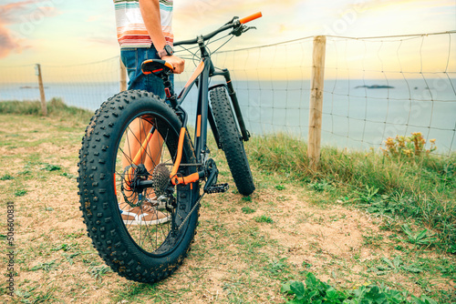 Fat bike on the coast with unrecognizable guy holding it photo