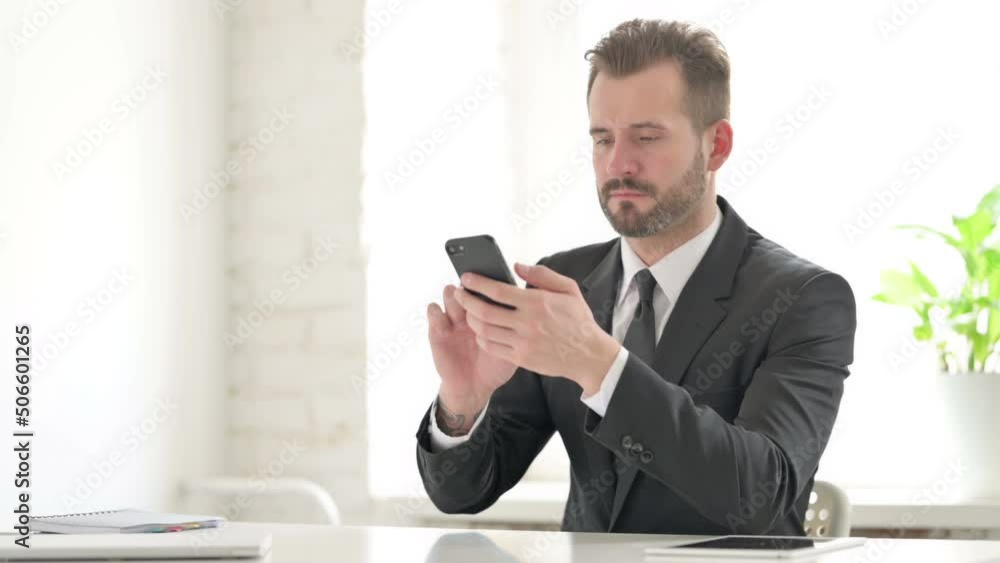 Attractive Young Businessman using Smartphone in Office Attractive Young Businessman using Smartphone in Office