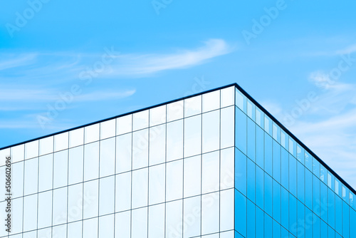 Low angle view of glass skyscraper with sunlight reflection on surface against blue sky background