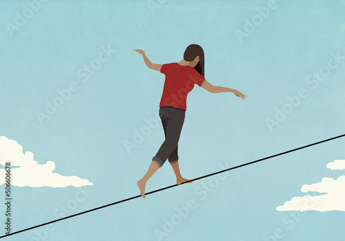 Barefoot woman walking along tightrope in sky
