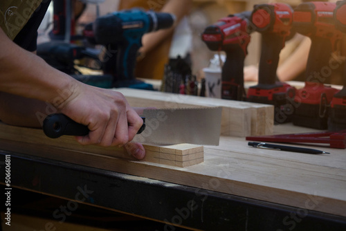 Carpenter working and sawing on wood craft at workshop to produce wooden furniture.