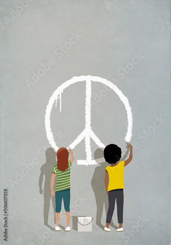 Multiracial girls painting peace sign on wall
 photo