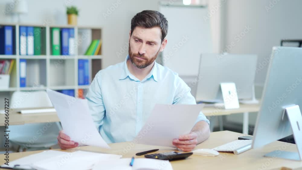 Difficult for a male employee to deal with paperwork. documents. Stressed caucasian businessman confused by mistake, looking through papers. bookkeeper, booker vaguely, dimly sitting at work in office Difficult for a male employee to deal with paperwork. documents. Stressed caucasian businessman confused by mistake, looking through papers. bookkeeper, booker vaguely, dimly sitting at work in office