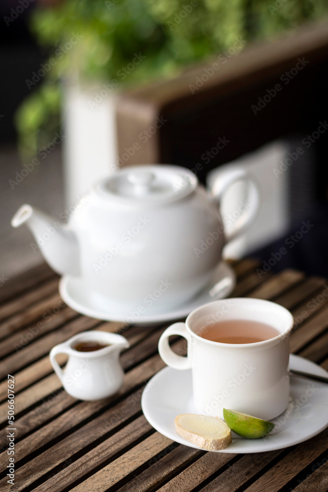 ginger tea pot and cup on wooden cafe table outdoors