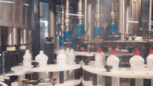 A robotic machine screw caps into bottles at the factory. Production of plastic containers