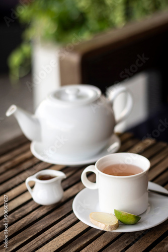 ginger tea pot and cup on wooden cafe table outdoors
