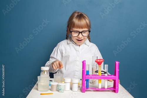 Happy child girl student doing science experiments in school laboratory on blue background