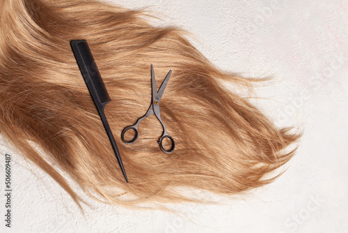 Brown hair, comb and scissors on white background