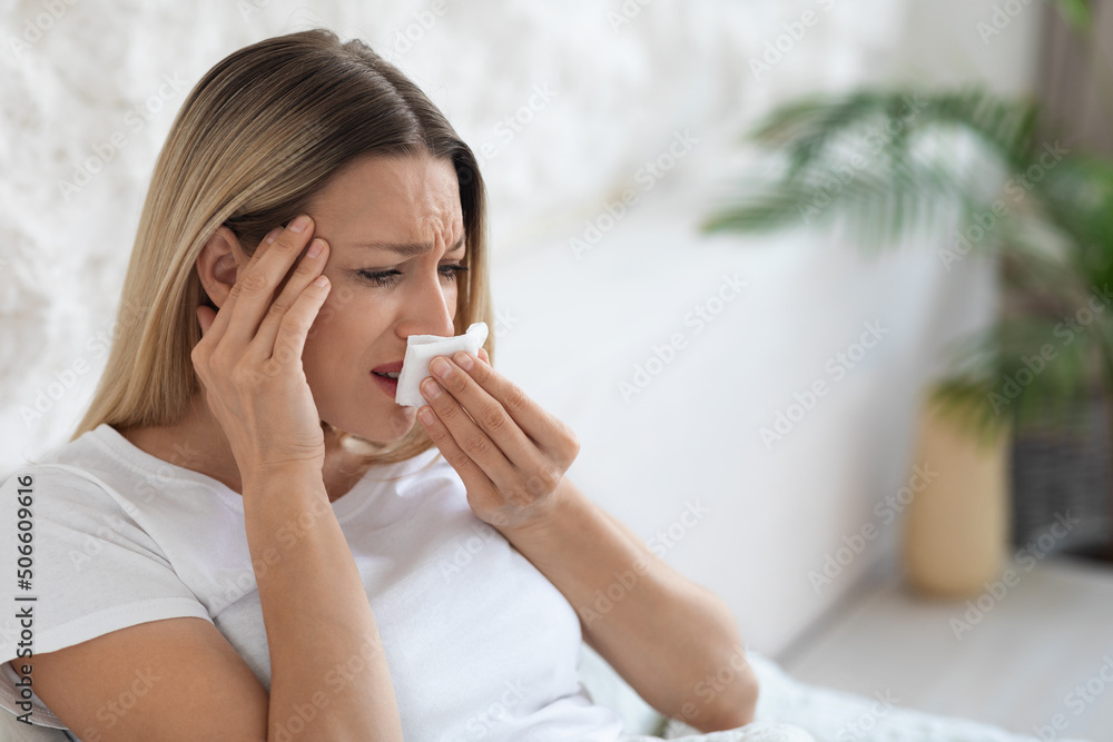 Ill blonde lady sneezing and touching her head Ill blonde lady sneezing and touching her head
