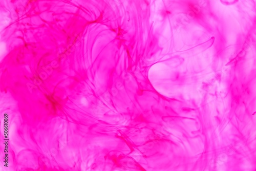 Shallow depth of field shot of swirling pink and blue ink in water - soft flowing abstract and soothing backdrop