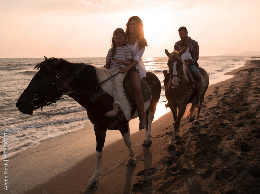 The family spends time with their children while riding horses together on a sandy beach. Selective focus The family spends time with their children while riding horses together on a sandy beach. Selective focus